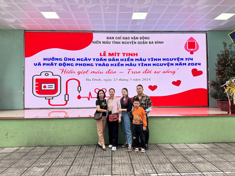 A group of people standing in front of a sign

Description automatically generated