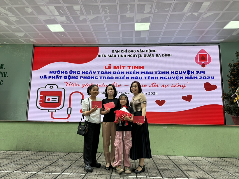 A group of people standing in front of a large sign

Description automatically generated