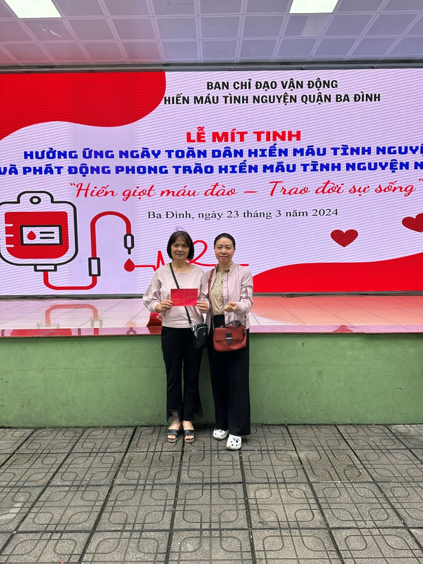 Two women standing in front of a sign

Description automatically generated
